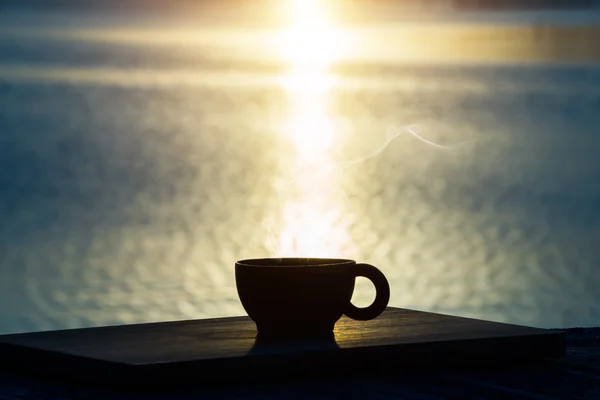 Siluetas de tazas de café en un lago con puesta de sol . — Foto de Stock