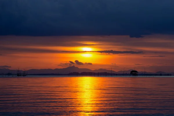 Bild des Sonnenuntergangs auf dem See unter dunklen Wolken. — Stockfoto