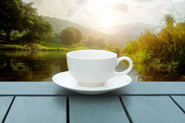 Filiżanka kawy biały na zielonym drewno w ranku. — Zdjęcie stockowe