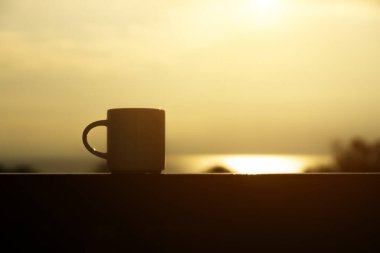 Sabah gökyüzünde siluet kahve fincanını kapat.