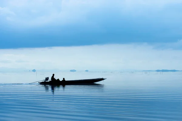 柔らかい光と青い時間で湖の上の漁船のシルエット — ストック写真