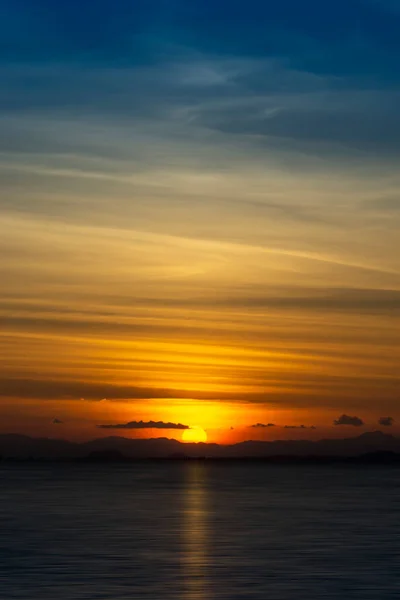 日没の空に太陽と線の雲とシルエットの山 — ストック写真