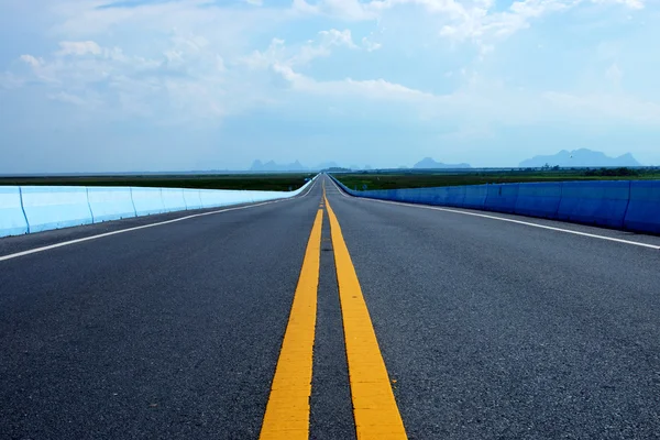 Lege weg en de gele verkeer lijnen met wolken. — Stockfoto