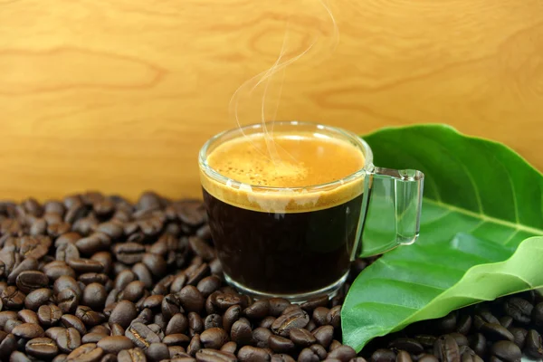 Granos de café arábica tostados negros y taza llena de café — Foto de Stock