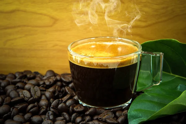 Granos de café arábica tostados negros y taza llena de café — Foto de Stock