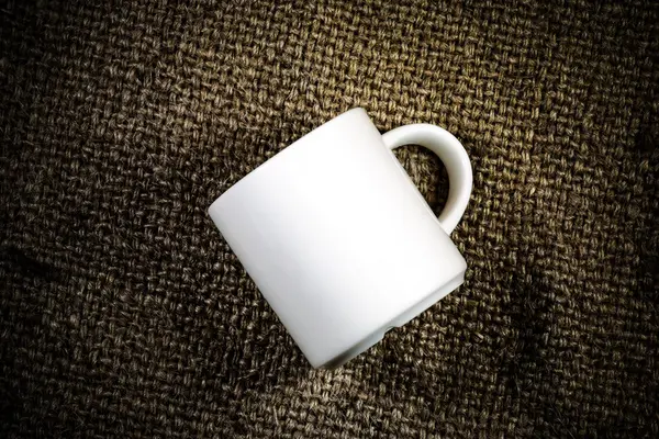 Taza de café blanco en un saco de cáñamo . — Foto de Stock