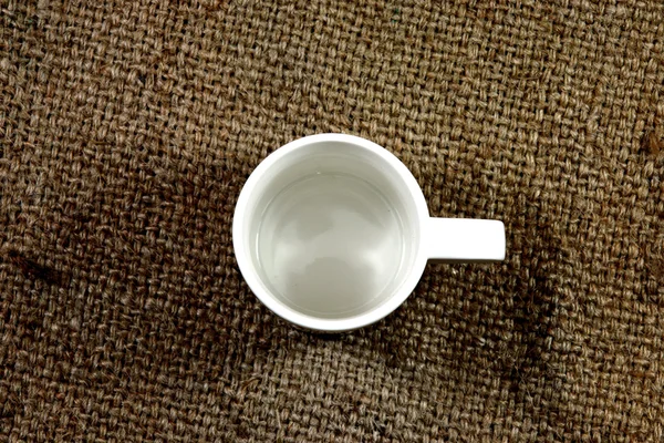 Copo de café branco em um saco de cânhamo . — Fotografia de Stock