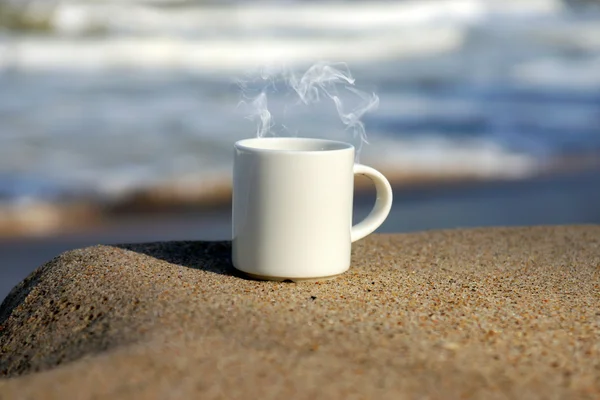 Filiżanka kawy biały na plaży. — Zdjęcie stockowe
