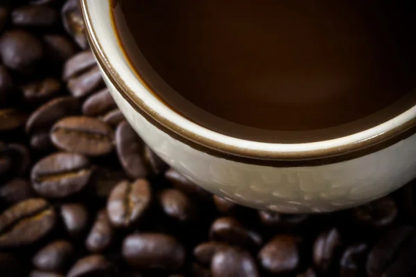 Close up van onscherpte geroosterde koffiebonen en warme koffie. — Stockfoto