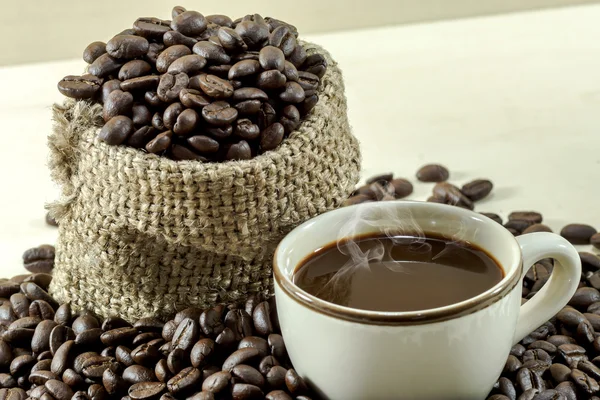 Roasted coffee beans and hot coffee — Stock Photo, Image