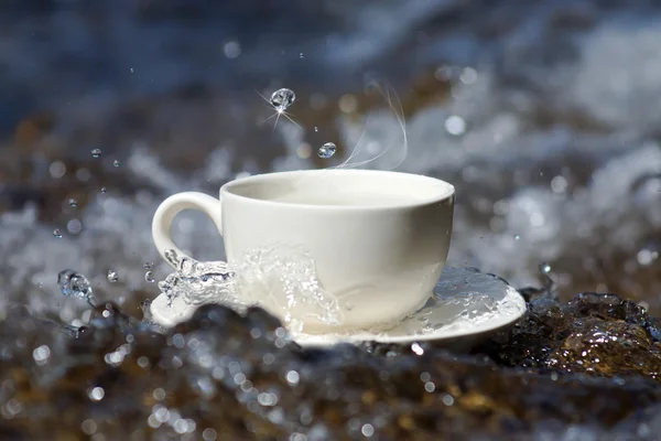 Water en koffie beker drankjes op de rotsen bij de watervallen — Stockfoto