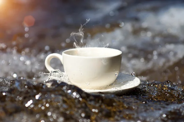 在瀑布的岩石上点心水和咖啡杯子 — 图库照片