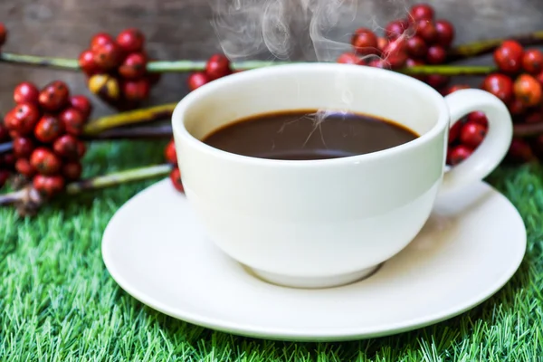 Kaffe och råa kaffebönor på konstgräs. — Stockfoto