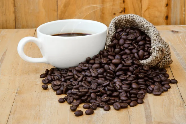 Heißer Kaffee auf dem Holz und geröstete Kaffeebohnen. — Stockfoto