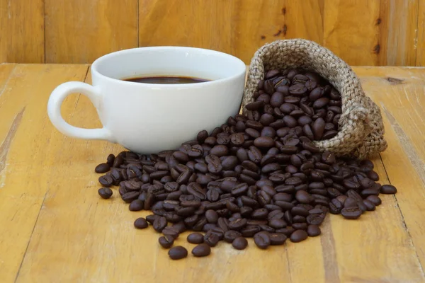 Café quente na madeira e torrado grão de café . — Fotografia de Stock