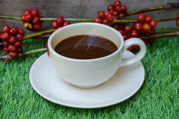 Kaffe och råa kaffebönor på konstgräs. Stockfoto