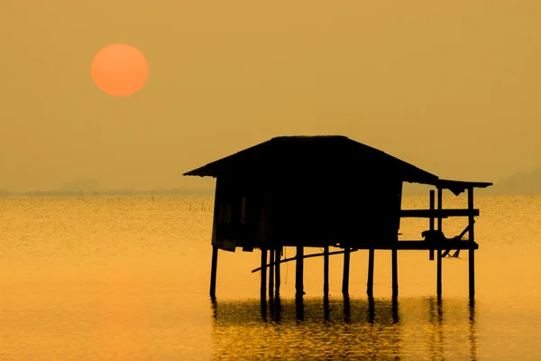Silhouetten eines alten Häuschens im See und Sonnenuntergang. — Stockfoto