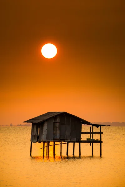 Silhouetten eines alten Häuschens im See und Sonnenuntergang. — Stockfoto