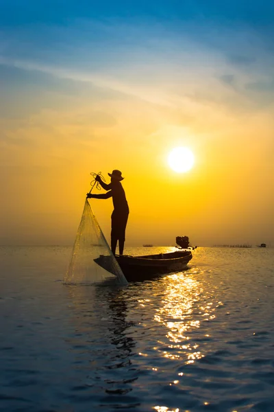 Silhouettes pêcheur jetant des filets de pêche au coucher du soleil . — Photo