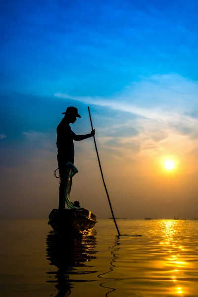 Siluetas pescador lanzando redes de pesca durante la puesta del sol . — Foto de Stock