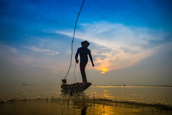 日没時に漁業用の網を投げるシルエット漁師. — ストック写真