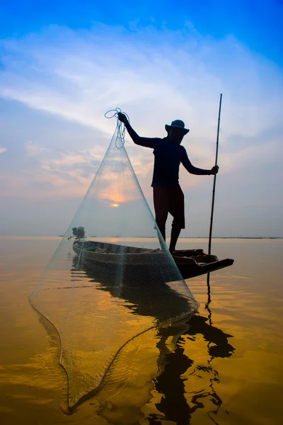 Silhuetas pescador jogando redes de pesca durante o pôr do sol . — Fotografia de Stock