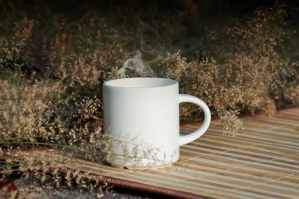 Kaffekopp med liten blomma gräs — Stockfoto