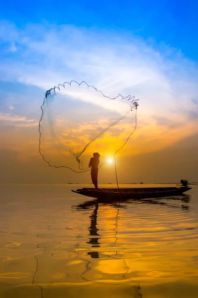 Silhuetter fisherman kasta fiskenät under solnedgången. Royaltyfria Stockbilder