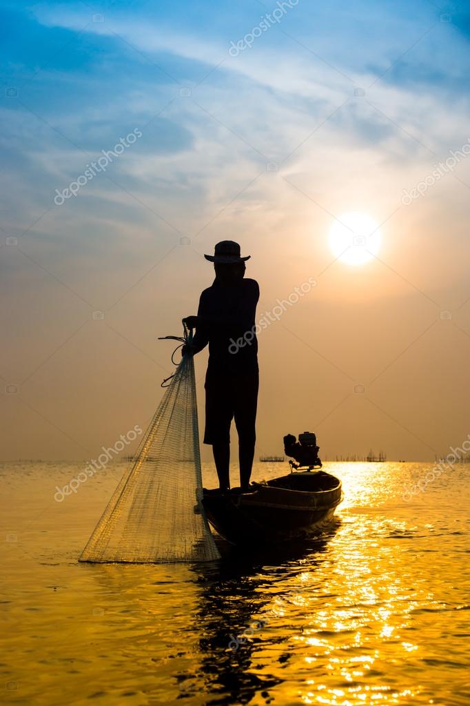 Silhouettes fisherman throwing fishing nets during sunset. Stock