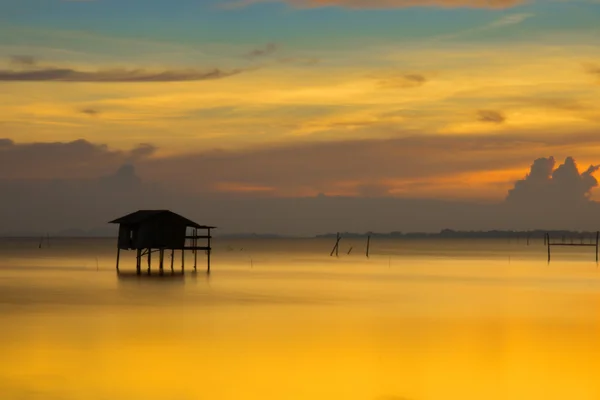 Silhouetten eines alten Häuschens im See und Sonnenuntergang. — Stockfoto