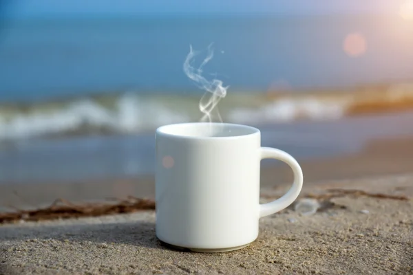 Witte koffiemok op het strand. — Stockfoto