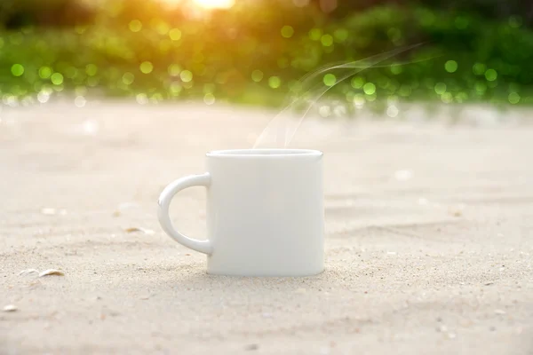 Witte koffiemok op het strand. — Stockfoto