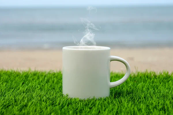 Taza de café blanco en la playa — Foto de Stock