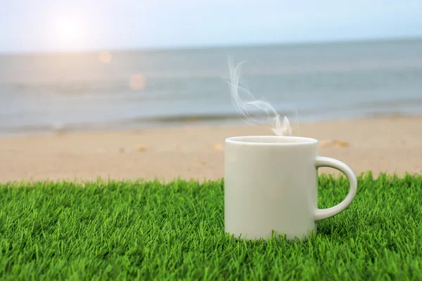 Taza de café blanco en la playa — Foto de Stock