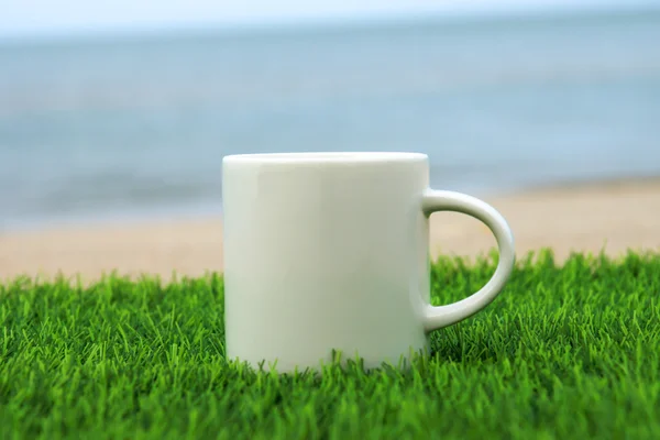 Witte koffiemok op het strand — Stockfoto