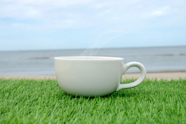 Witte koffiekopje op het strand — Stockfoto