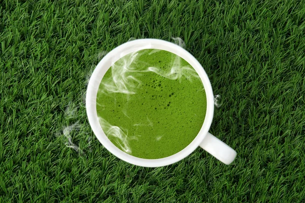 Green tea cup on the artificial turf. — Stock Photo, Image