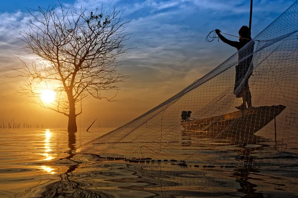 Silhuetter fisherman kasta fiskenät under solnedgången, Thail — Stockfoto