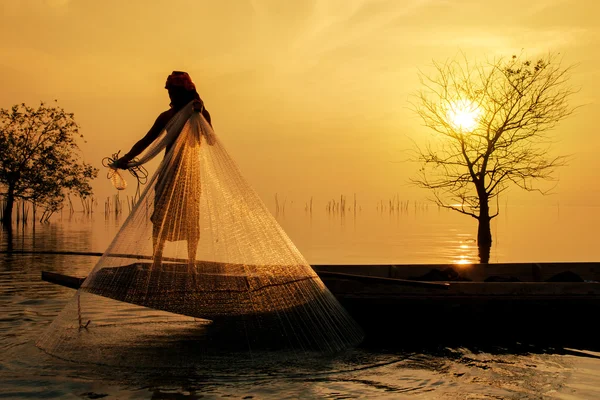 Siluetas pescador lanzando redes de pesca durante la puesta del sol, Thail —  Fotos de Stock