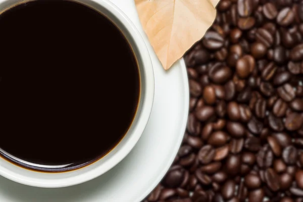 Black coffee in the cup and blur roasted coffee beans background — Stock Photo, Image