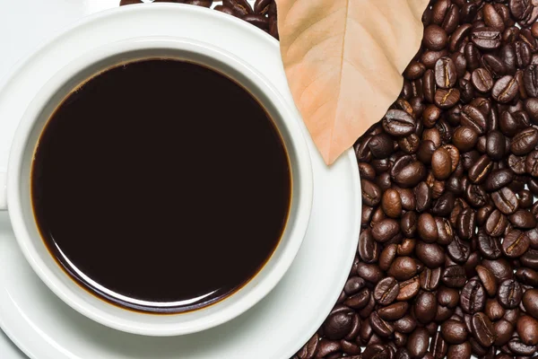 Svart kaffe i koppen och rostade kaffebönor bakgrund. Stockbild