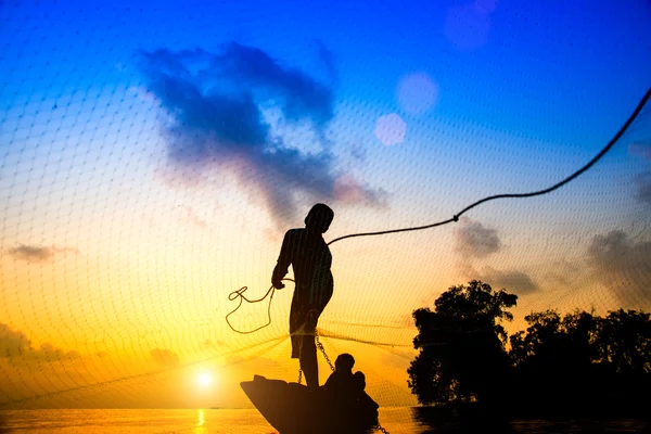 Silhouettes pêcheur jetant des filets de pêche au coucher du soleil, Thail — Photo