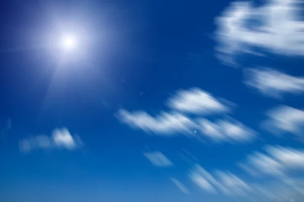 Pohyb obrazu bílých oblaků s slunce na modré obloze. — Stock fotografie
