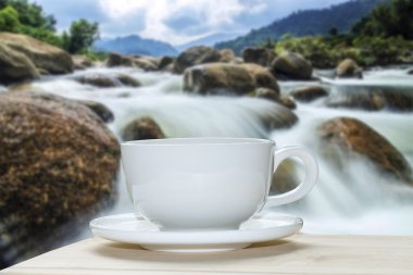 Beyaz kahve fincanı ile küçük şelale arka plan bulanıklık.