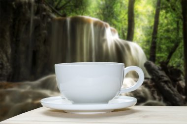 Beyaz kahve fincanı ile şelale arka plan bulanıklık.