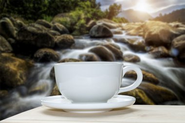 Beyaz kahve fincanı ile küçük şelale arka plan bulanıklık.