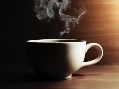 Karanlıkta ışık ile ahşap üzerine kahve fincanı.