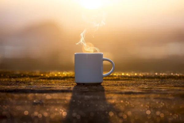 Чашка белого кофе в утреннее время с восходом солнца . — стоковое фото
