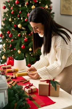 Bir insanın güzel dekore edilmiş bir ağacın yanında hediyeleri sararken mutlu bir Noel kutlaması.