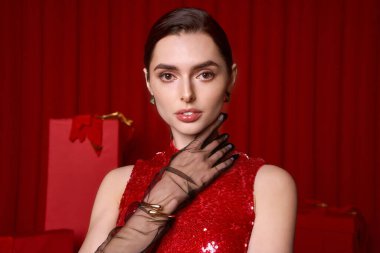 Canlı kırmızı şenlikli bir kadın şık bir tatil atmosferinde zarifçe poz verir..